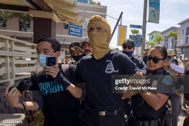 Police officers take a rally supporter in custody to a police substation near a "White Lives Matter" rally on April 11, 2021 in Huntington Beach,...