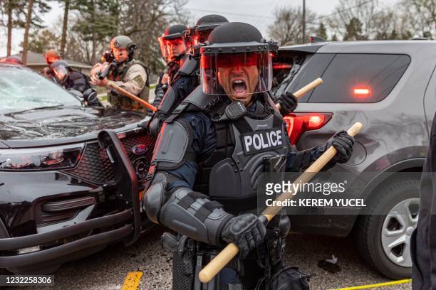 Police officers take cover as they clash with protesters after an officer shot and killed a black man in Brooklyn Center, Minneapolis, Minnesota on...