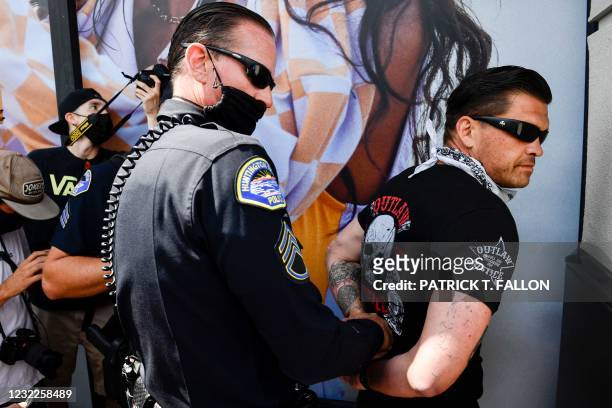 Man with a skull tattoo on his left arm resembling a Totenkopf is arrested by Huntington Beach police as anti-racism protesters confronted supporters...