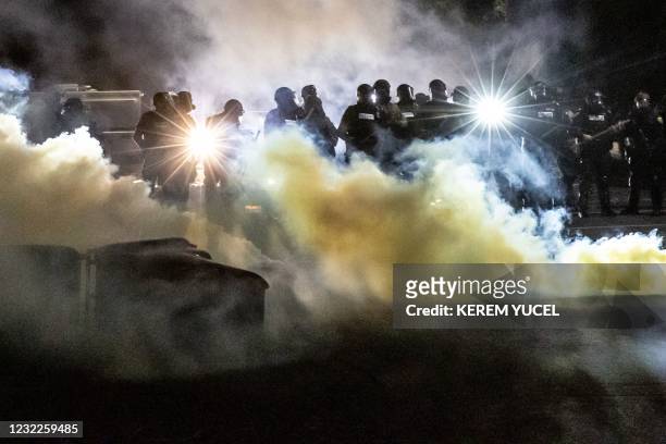 Police officers in riot gear fire tear gas in front of the Brooklyn Center Police Station as people gather to protest after a police officer shot and...