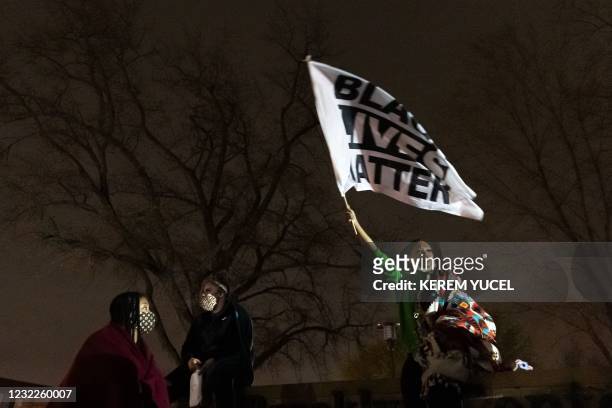Woman holds up a "Black Lives matter" flag as protestors gather in front of the Brooklyn Center Police Station after an officer shot and killed a...