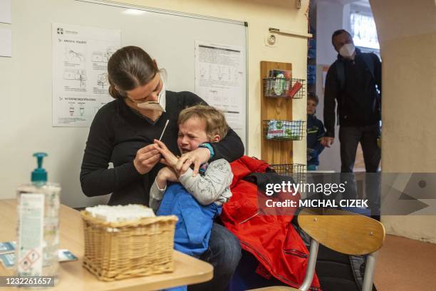 Mother tests her child on Covid-19 at a kindergarten on April 12, 2021 in Prague as kindergartens and primary schools re-opened as some restrictions...