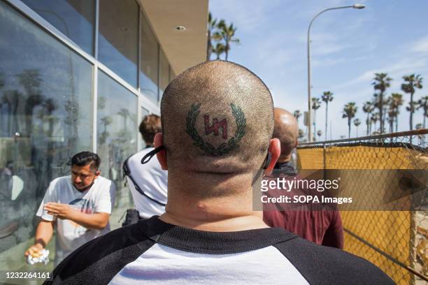 Man with a tattoo on the back of his head related to neo-Nazi groups walks away from the protesting crowd after partaking in a physical altercation...