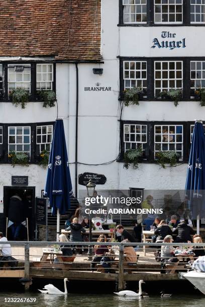 People sit in the afternoon sunshine in the garden of The Angel on the Bridge pub in Henley-on-Thames, west of London on April 12, 2021 as...