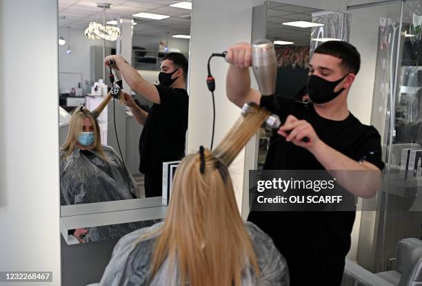 Customers get their hair cut at a re-opened hairdresser's salon in Liverpool, north west England, as coronavirus restrictions are eased across the...