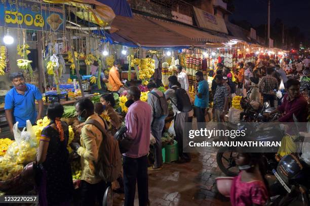 People shop for fruits and flower garlands on the eve of Ugadi festival in Bangalore on April 12, 2021.