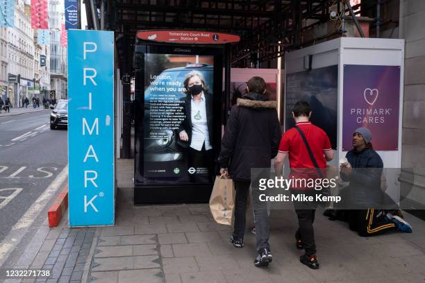 Man kneeling on the pavement begging for money as shoppers return to Primark on Oxford Street as non-essential shops reopen and the national...
