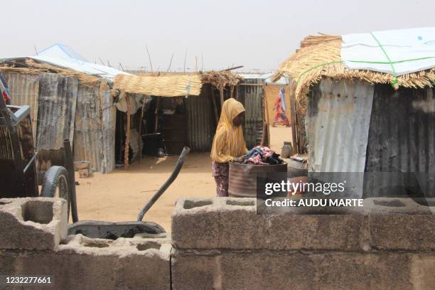 Woman stands between structures Yawuri informal camp on the outskirts of Maiduguri, capital of Borno state, on March 29, 2021. - The makeshift camp...