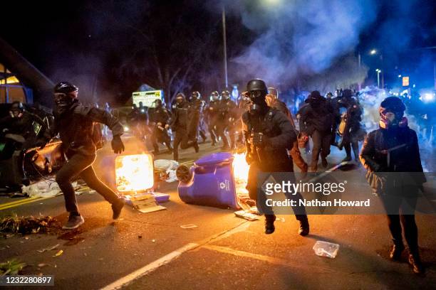 Portland police officers chase demonstrators after a riot was declared during a protest against the killing of Daunte Wright on April 12, 2021 in...