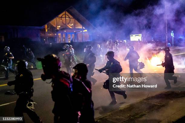 Portland police officers chase demonstrators after a riot was declared during a protest against the killing of Daunte Wright on April 12, 2021 in...