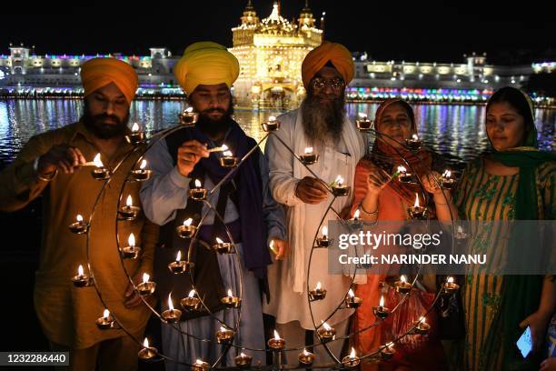 Sikh devotees light candles on the occasion of the Baisakhi festival at the Golden Temple, in Amritsar on April 13, 2021.