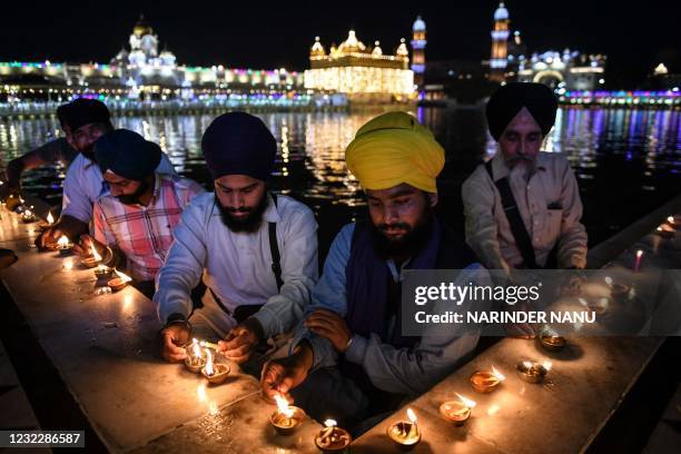 Sikh devotees light candles on the occasion of the Baisakhi festival at the Golden Temple, in Amritsar on April 13, 2021.