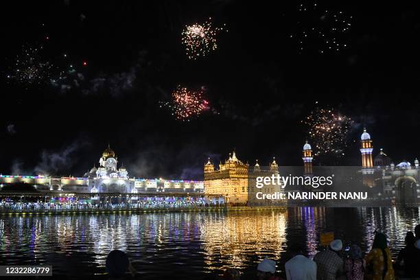 Sikh devotees watch fireworks at the Golden Temple on the occasion of the Baisakhi festival, in Amritsar on April 13, 2021.