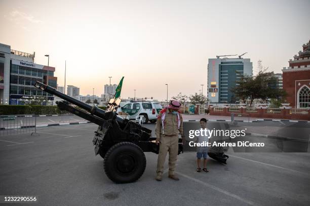 Police officer takes photos with a young Emirati boy before he prepares to fire a cannon, a decades long Emirati tradition, at Al Salam Mosque in Al...