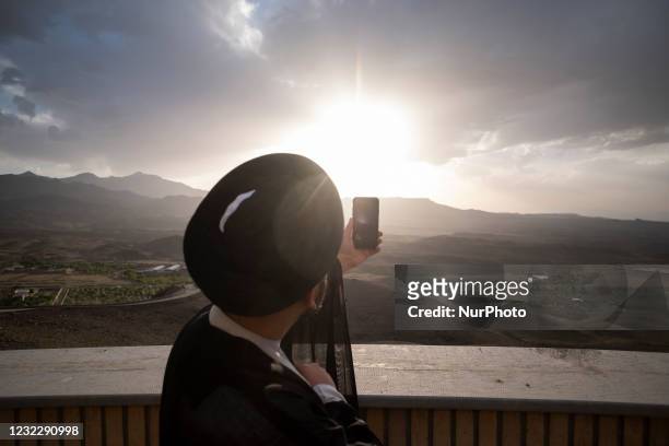 An Iranian cleric uses an application on his smartphone to find the new moon of Muslims holy month of Ramadan while standing in the Imam Ali...