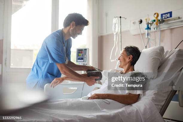 eine männliche krankenschwester nimmt den puls einer weiblichen patientin. - adult male hospital bed stock-fotos und bilder