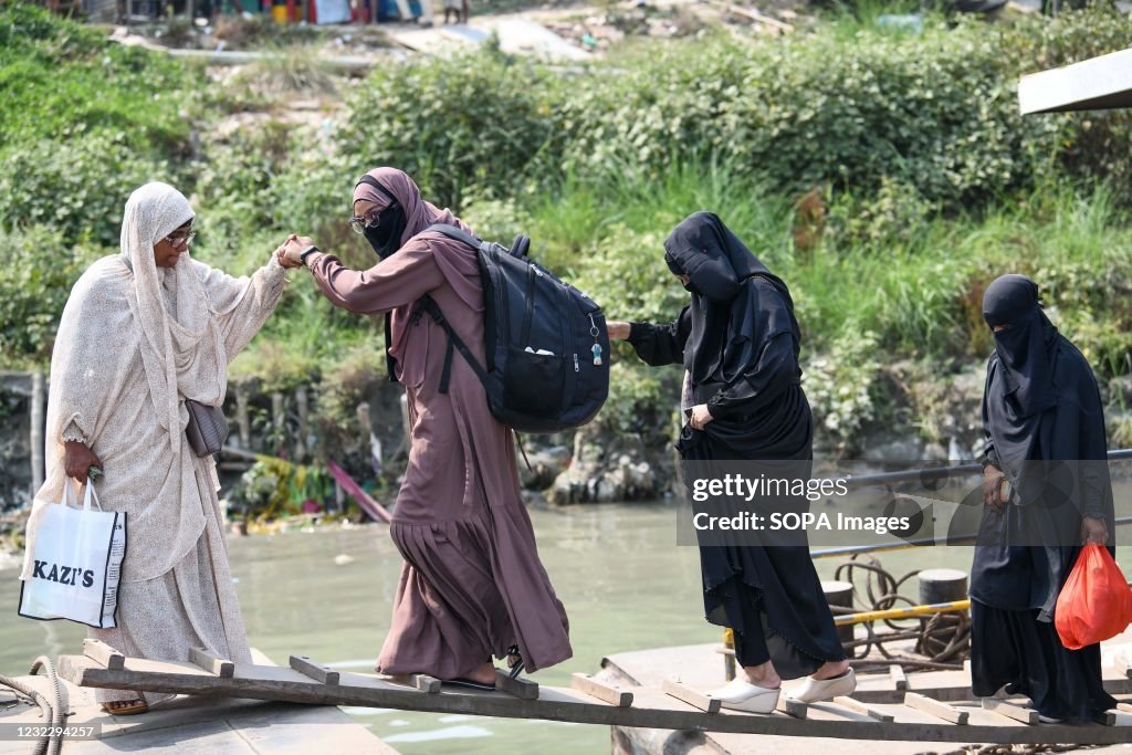 A woman helps another walk on a bridge to the speed boat as...