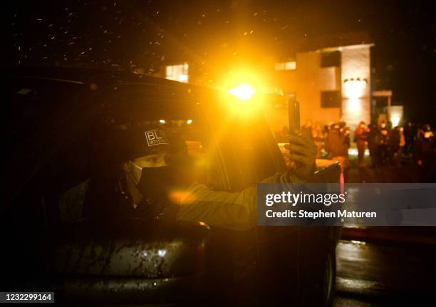 Man films on his mobile phone as protesters confront law enforcement outside the Brooklyn Center police headquarters on April 13, 2021 in Brooklyn...