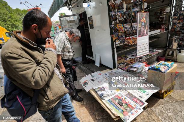 Men view the covers of local newspapers laid out at a stall in the Shemiran district of Iran's capital Tehran on April 14, 2021. - Iran warned it...