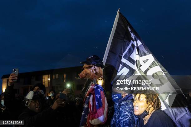 Demonstrators brandish a pig's head on a pike and fly a Black Lives Matter flag outside the Brooklyn Center police station while protesting the death...