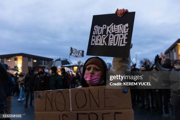 Demonstrator holds a sign reading "Stop Killing Black People" as she stands outside the Brooklyn Center police station while protesting the death of...