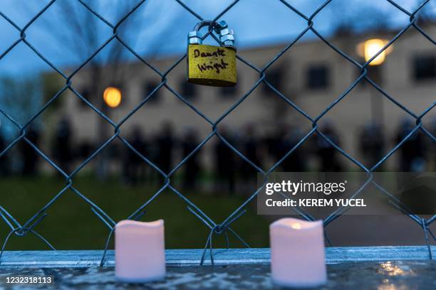 Padlock, with the name of Daunte Wright written on it, hangs from a security chain-link fence outside the Brooklyn Center police station as...