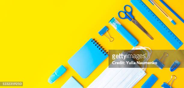 back to school, school supplies with medical face mask on a yellow background. protection of schoolchildren and students from the virus, schooling in a pandemic. flat lay, the layout of the school. welcome back to school. top view, copy space. - background paint room stock-fotos und bilder