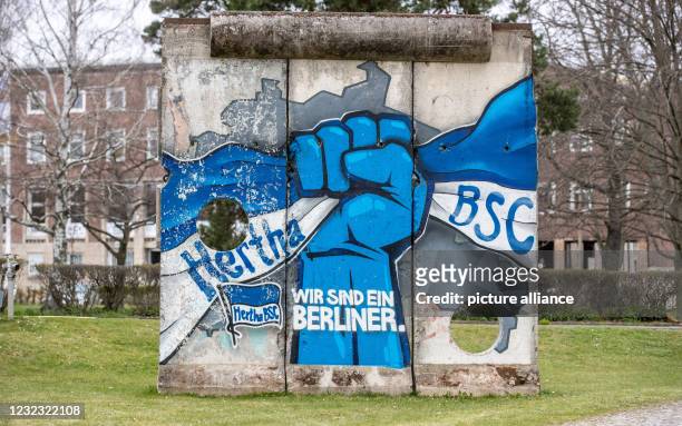 April 2021, Berlin: A piece of the Berlin Wall in front of Hertha BSC's offices bears the words: Wir sind eine Berliner. The Bundesliga soccer club...