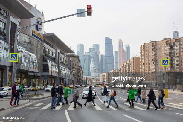 Pedestrians cross a street in front of skyscraper office buildings situated in the Moscow International Business Center , also known as 'Moscow...