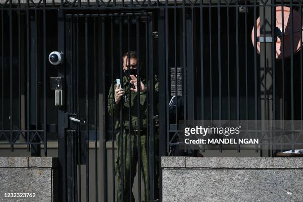 Security guard at the Russian Embassy in Washington, DC, aims his phone camera at media gathered outside on April 15, 2021. - The US announced...