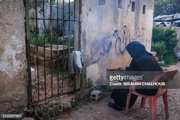 Woman grills chicken near a grave, as she prepares the fast-breaking "Iftar" meal, consumed after sunset during the Muslim holy month of Ramadan, in...