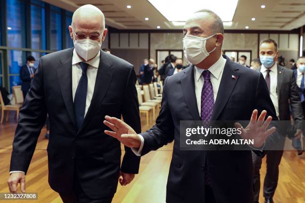 Turkish Foreign Minister Mevlut Cavusoglu speaks with Greek Foreign Minister Nikos Dendias as they arrive to the press conference following their...