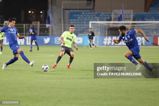 S defender Akramjon Komilov passes the ball through Hilal's defender Jang Hyun-soo and Hilal's defender Mohammed al-Breik during the AFC Champions...