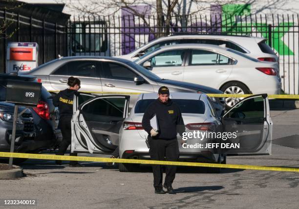 Crime scene investigators walk through the parking lot of the mass shooting site at a FedEx facility in Indianapolis, Indiana, on April 16, 2021. - A...