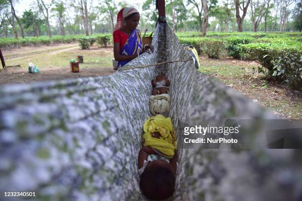 An Indian tea plantation worker rocks her child in a cloth hammock at a tea garden in Nagaon district, in the northeastern state of Assam, India on...
