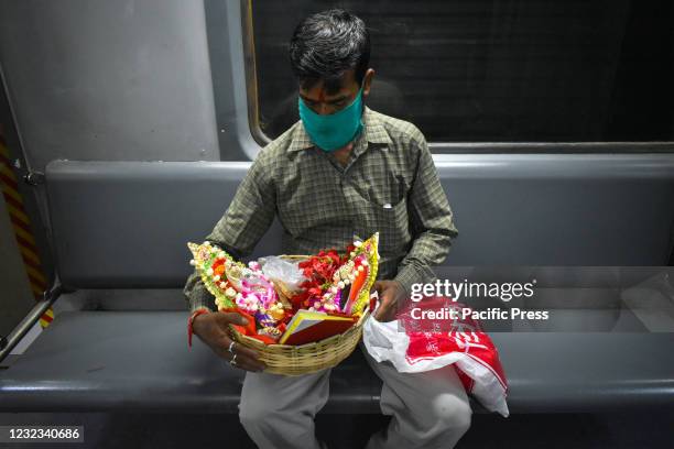 Man wearing protective mask carrying Hindu god Lakshmi and Ganesh on the occasion of Bengali's New Year, inside a Metro rail amid the spread of...