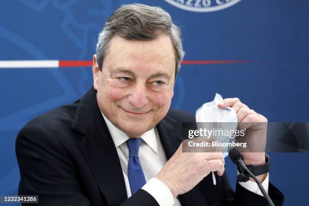 Mario Draghi, Italy's prime minister, removes his protective face mask during a news conference in Rome, Italy, on Friday, April 16, 2021....