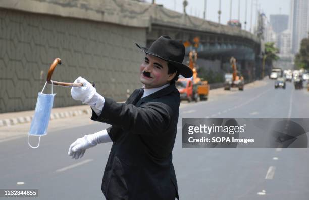 Man dressed as Charlie Chaplin hangs a facemask on a stick to create awareness about coronavirus disease in Mumbai. The covid-19 awareness drive to...