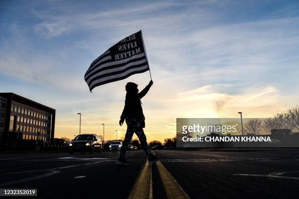 Demonstrator marches, holding a Black Lives Matter flag, during the sixth night of protests over the shooting death of Daunte Wright by a police...