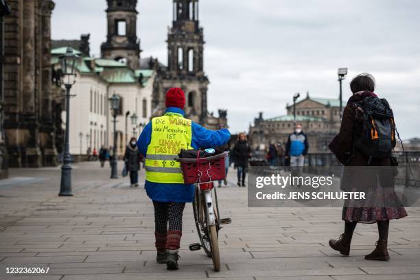 Woman wearing a vest with the lettering 'The dignity of humans is inviolable', with reference to the first article of the German Constitution, walks...