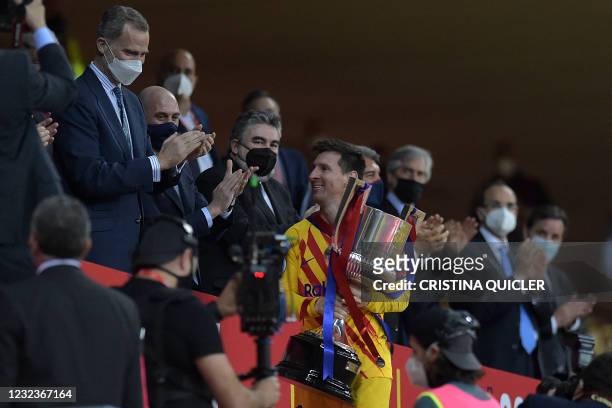 Barcelona's Argentinian forward Lionel Messi holds the trophy after receiving it from Spain's King Felipe VI at the end of the Spanish Copa del Rey...