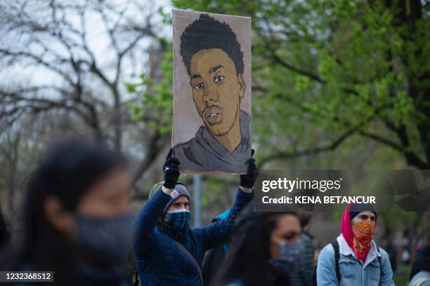 Man holds up a placard as people leave items at a makeshift memorial in honor of Daunte Wright, who was shot dead by a police officer in Minneapolis,...