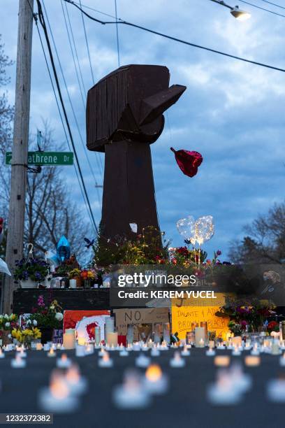 People gather around a makeshift memorial for Daunte Wright at a sculpture of a raised fist in Brooklyn Center, Minnesota on April 17, 2021. - Kim...