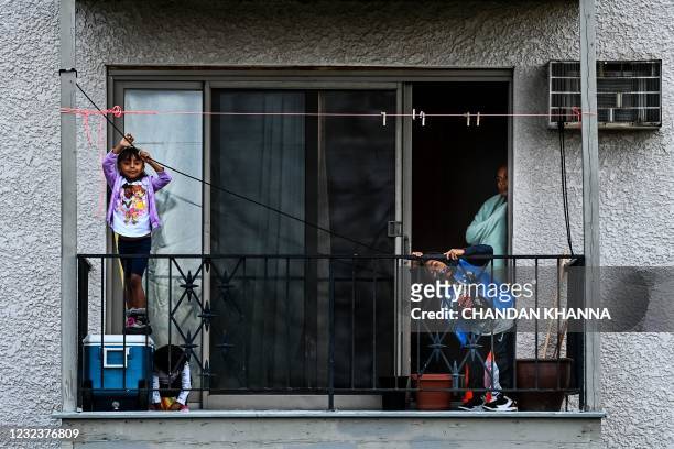 Children play on the balcony of their house as demonstrators gather during the seventh night of protests over the shooting death of Daunte Wright by...