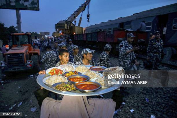 Woman carries a tray loaded with food, for people to break their Ramadan fast, as she walks towards Egyptian security forces standing guard near a...