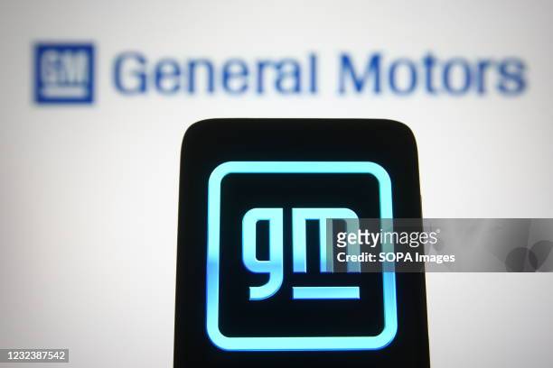 In this photo illustration, the General Motors logo seen displayed on a smartphone and a pc screen.