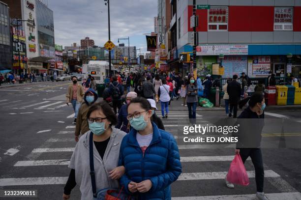 Pedestrians make their way along a street in Flushing, in the New York borough of Queens on April 18, 2021. - Anti-Asian hate crimes almost tripled...