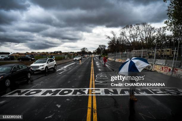 Demonstrator stands under an umbrella during a rainfall as he protests over the shooting death of Daunte Wright by a police officer in Brooklyn...