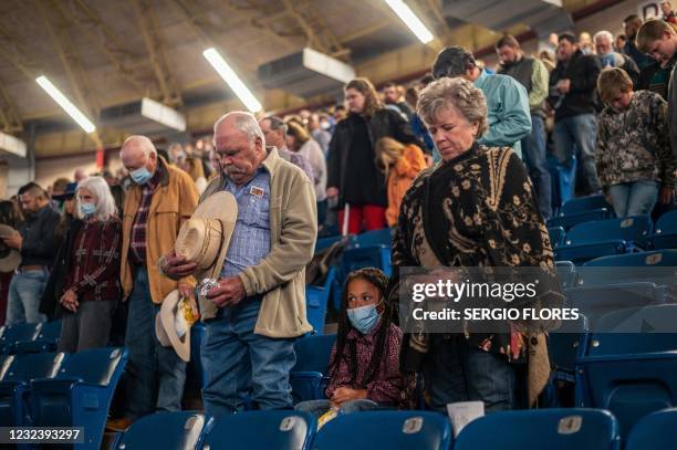 People inside the Foster Communications Coliseum bow their heads in a prayer before the start of the San Angelo Stock Show and Rodeo, April 16, 2021...