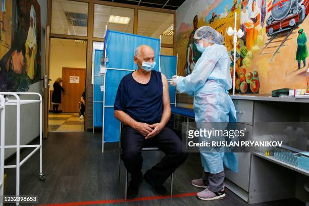 An elderly man receives a dose of the Sputnik V vaccine against the coronavirus disease at a vaccination point in the Abylkhan Kasteyev State Museum...